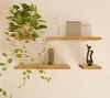A wall with three wooden shelves displaying various decorative items and a plant. Produktbild-Vorschau
