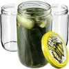 Three glass jars, one filled with pickles, and a yellow lid with a floral design. Produktbild-Vorschau