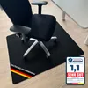 A black office chair is placed on a black floor mat in front of a white desk. Náhled obrázku produktu