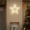 A lit-up star decoration hangs above a fireplace with a Christmas tree to the right. Podgląd zdjęcia produktu