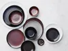A collection of plates and bowls arranged on a light gray surface. Produktbild-Vorschau