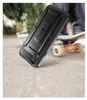 A black phone case with a kickstand is shown on a concrete surface next to a skateboard. Produktbild-Vorschau