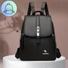 A black leather backpack is displayed on a white pedestal against a brown background. A small graphic of a backpack is in the upper left corner, connected by a dashed line to the main product. Voir les images du produit