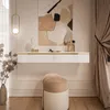 A modern dressing table setup with a floating white vanity, a decorative stool, and artwork above. Náhled obrázku produktu