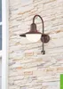 A brown outdoor wall light mounted on a stone-tiled wall. Produktbild-Vorschau