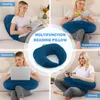 A collage of four images showing a navy blue U-shaped pillow being used for reading, breastfeeding, working on a laptop, and gaming, with a central image of the pillow itself. Produktbild-Vorschau