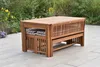 A wooden garden furniture set on a paved patio with greenery in the background. Produktbild-Vorschau