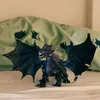 A toy dragon is placed on a bed with a patterned sheet in the background. Voir les images du produit