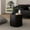 A dark wooden round coffee table with books and a cup on it, placed next to a sofa and a large framed picture of a tree. Podgląd zdjęcia produktu