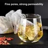 A close-up of tea bags and goji berries next to a glass of tea. Produktbild-Vorschau