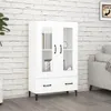 A white cabinet with glass doors and drawers is shown against a white brick wall. Náhled obrázku produktu