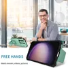 A man is sitting at a table in a cafe, looking at his phone which is in a protective case with a stand. The phone case is turquoise and black. Produktbild-Vorschau