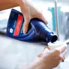 A person is pouring cleaning liquid from a blue bottle into a white measuring cup. Voir les images du produit
