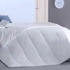 A white duvet is laid out on a bed, with a blue pillow and an open book visible at the top left. Produktbild-Vorschau