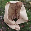 A small tree covered with burlap fabric, placed on a grassy area with fallen leaves. Náhled obrázku produktu