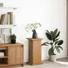 A wooden pedestal with a vase of flowers and a potted plant next to it, placed in a room with shelves and a cabinet. Voir les images du produit