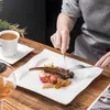 A person is eating a meal of lamb chops with sides of tomatoes and fries, accompanied by a cup of coffee and a glass of wine. Produktbild-Vorschau