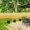 A backyard scene with a wooden deck, a fence, and outdoor furniture. Produktbild-Vorschau