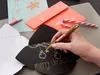 A hand is writing on a black card with a gold marker, surrounded by Christmas cards and a candy cane. Produktbild-Vorschau