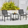 Two gray outdoor chairs and a small black side table are set up on a patio next to some lush green plants. Produktbild-Vorschau