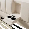 A close-up view of a beige upholstered bed frame's headboard, showing integrated cup holders and a control panel with USB and Type-C ports. Anteprima dell’immagine prodotto