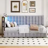 A modern bedroom with a grey upholstered daybed, decorated with pillows and a throw blanket. The wall above the bed features framed artwork and subtle LED lighting. Anteprima dell’immagine prodotto