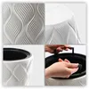 A collage of four images showing details of a white planter with a textured wavy pattern and a black inner pot, including close-ups of the texture and a hand holding the inner pot's handles. Náhľad obrázku produktu