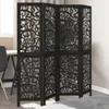 A black room divider with intricate cutouts is placed in a room, partially obscuring a desk and chair. Voir les images du produit