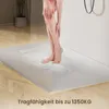 A person's legs are shown standing on a white shower tray while water is spraying. Náhľad obrázku produktu