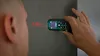 A person is using a laser distance measurer to measure the distance to a wall. Produktbild-Vorschau