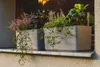 Two planters filled with plants on a windowsill. Náhled obrázku produktu