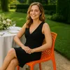 A woman sits at a table set for a meal outdoors in a garden. Produktbild-Vorschau