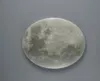 A close-up, top-down view of a decorative moon-shaped light fixture against a plain gray background. Náhled obrázku produktu