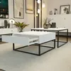 A modern living room with two white coffee tables with black metal frames, one with an open drawer, placed on a light gray rug. Produktbild-Vorschau