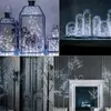 Collage of decorative lighting elements including lanterns filled with lights, glass domes with lights, and illuminated trees. Voir les images du produit