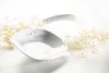 Two white ceramic bowls with black speckle accents are arranged on a white surface, with dried floral sprigs around them. Produktbild-Vorschau
