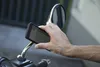 A hand holding a smartphone with navigation displayed, attached to a motorcycle mirror. Anteprima dell’immagine prodotto