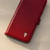 A close-up, angled shot of a red leather phone case with a bull logo. Produktbild-Vorschau