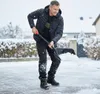 A man is shoveling snow in a driveway during a snowfall. Produktbild-Vorschau