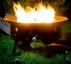 A gas fire pit is burning on grass at night. Produktbild-Vorschau