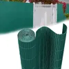 A roll of green privacy screen fencing is shown in the foreground, with a section of installed green privacy screen fencing and a white gate in the background. Náhled obrázku produktu