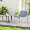 A two-piece outdoor furniture set, consisting of a chair and a small table, is placed on a paved patio area next to a grassy lawn. Lush green plants and a white fence form the background. Podgląd zdjęcia produktu