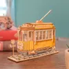 A wooden model of a yellow tram on a wooden track, with books and a plant in the background. Produktbild-Vorschau