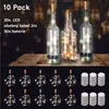 Three glass bottles with corks and LED string lights inside, placed on a wooden table. Below are multiple coiled LED string lights and stacks of batteries. Anteprima dell’immagine prodotto