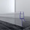 A clear plastic shower seal with a purple fitting is shown attached to a glass shower door, resting on a tiled floor. Produktbild-Vorschau