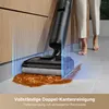 A person is using a cordless vacuum cleaner to clean up a spill on a hard floor next to kitchen cabinets. Produktbild-Vorschau