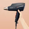 A hand holds a black Panasonic hair dryer with rose gold accents against a light peach background. Anteprima dell’immagine prodotto