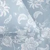 A close-up view of a light blue fabric with a white floral pattern. Podgląd zdjęcia produktu