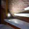 A motion-activated LED light is mounted on a step of a staircase, illuminating the brick wall and the steps. Produktbild-Vorschau
