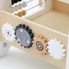 A close-up view of the side panel of a wooden baby walker, showcasing several colorful gears and an abacus. Produktbild-Vorschau